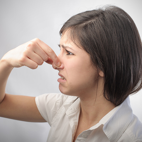 Woman with short brown hair holding nose from smell